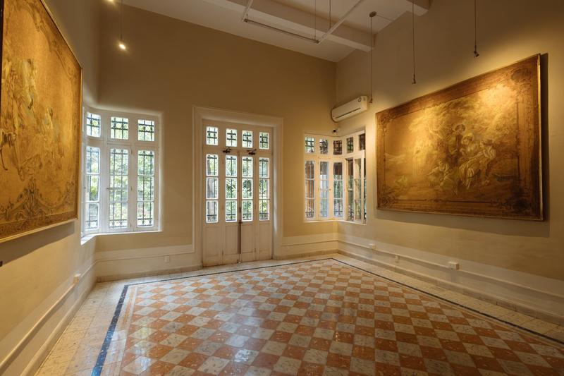 Salón secundario con piso naranja, ventanales y cuadros